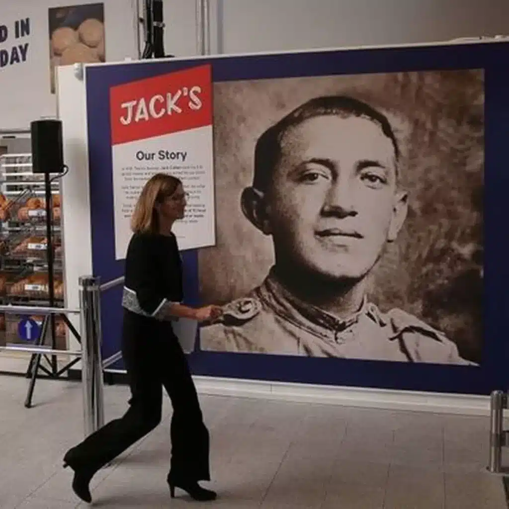 0 woman walks past poster about jack cohen in a tesco store